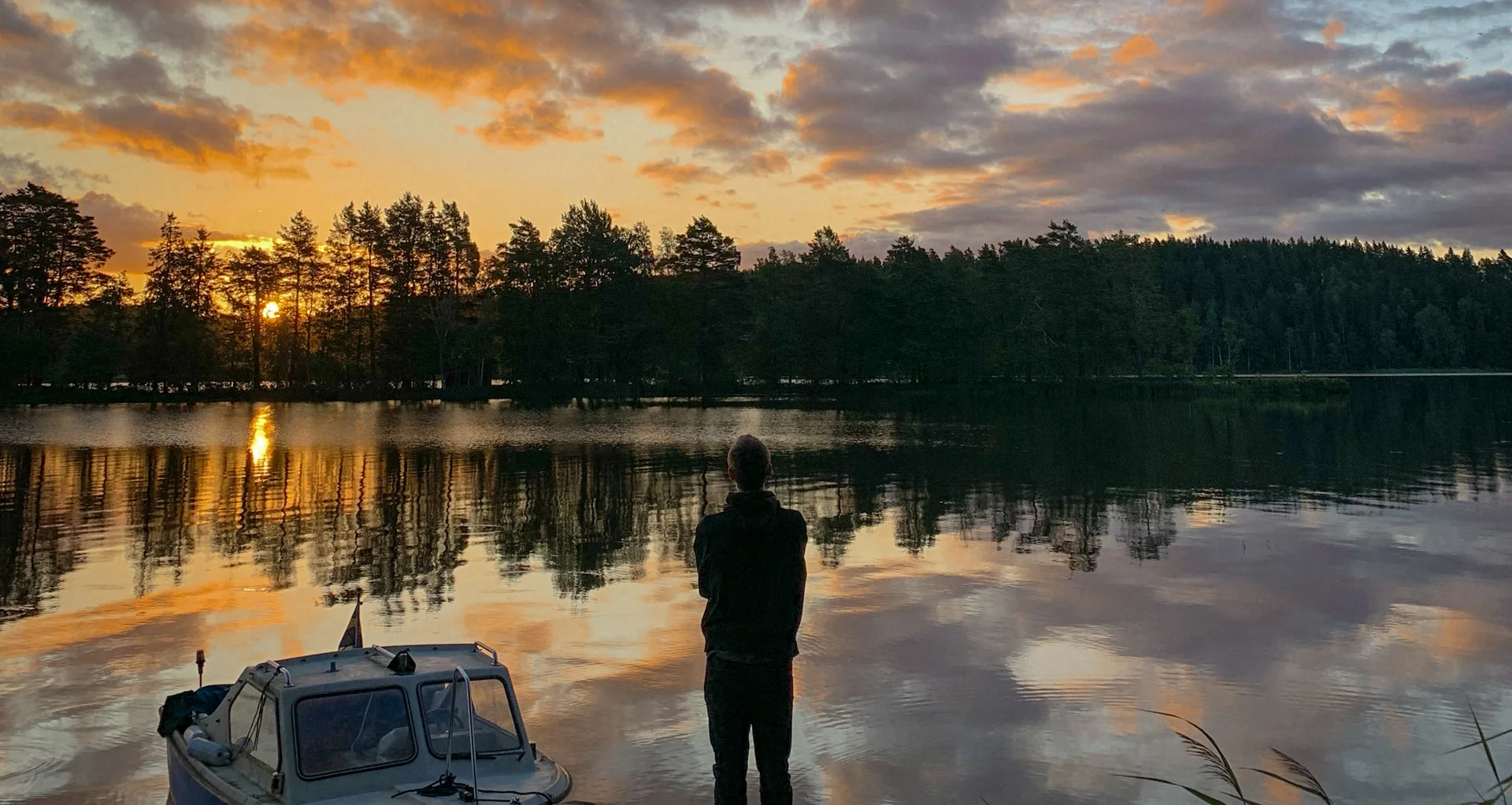 Person in einem Boot auf einem See im Abendlicht